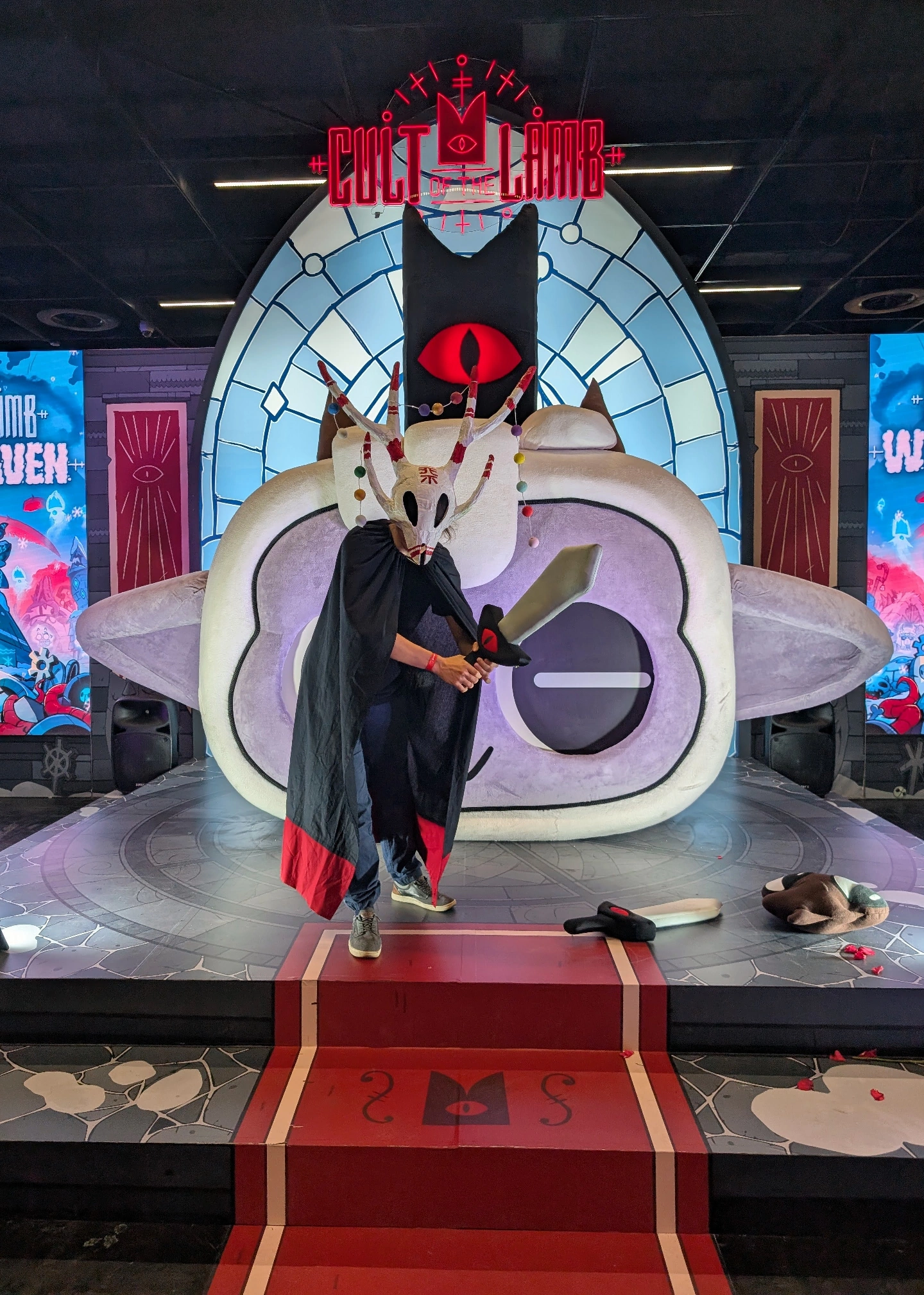 A selfie of myself wearing the outfit holding a plush sword on the Cult of the Lamb set.